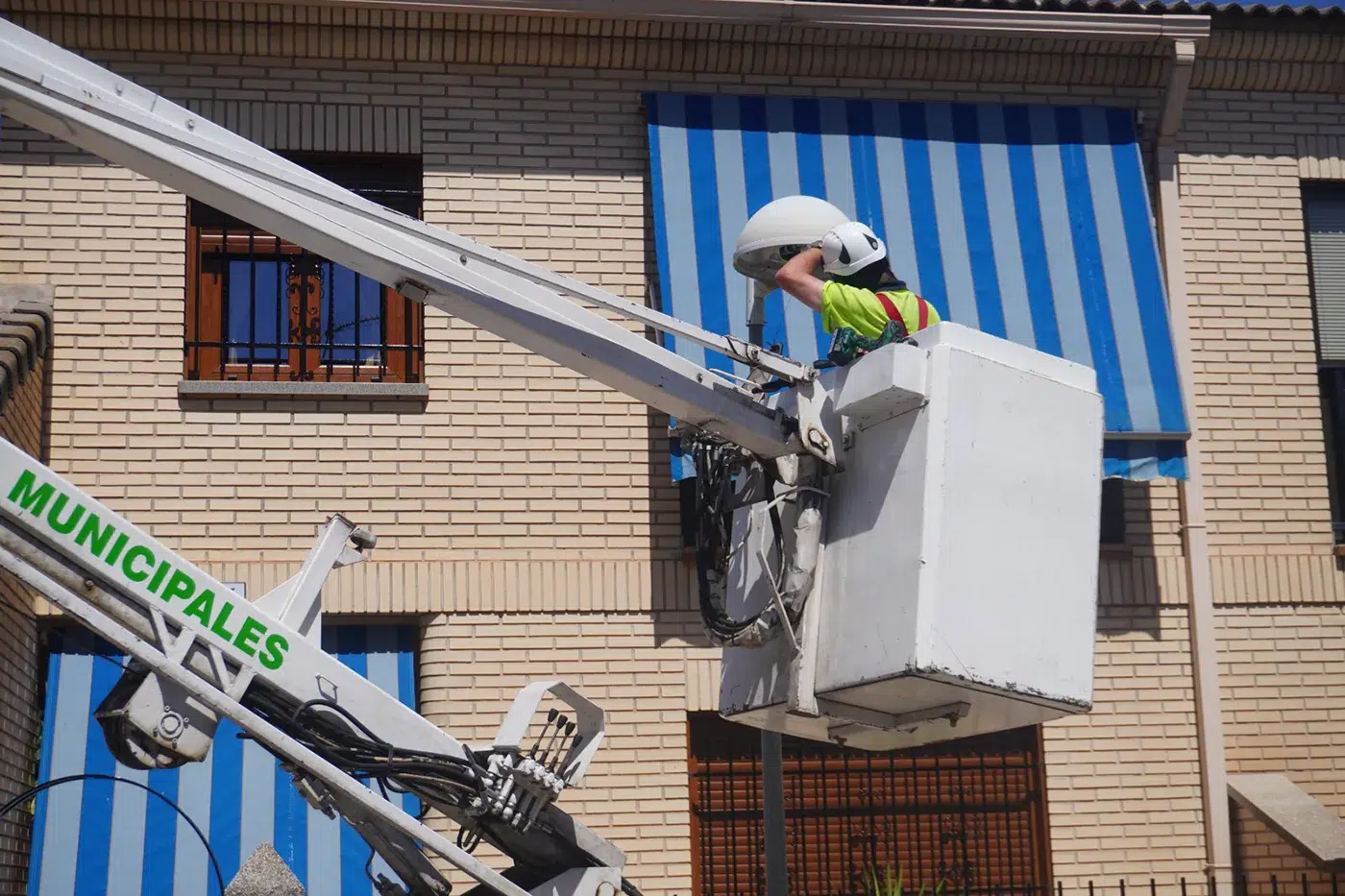 Operarios municipales realizan la instalación de luminarias LED en una calle de Torrijos.