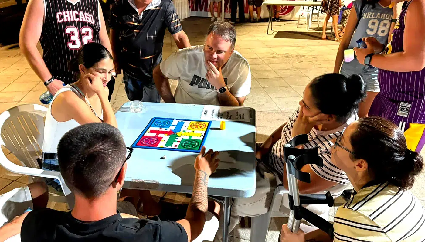 Participantes jugando en mesas durante el XXVI Maratón de Parchís de Camarena en el Paseo de la localidad